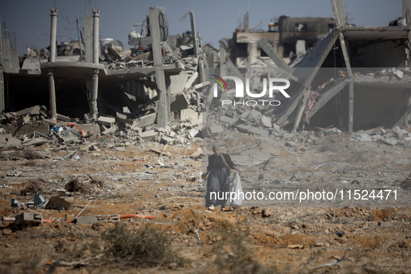 Palestinians collect their belongings and inspect the destruction caused by Israeli airstrikes in eastern Deir al-Balah in central Gaza Stri...