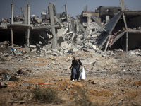 Palestinians collect their belongings and inspect the destruction caused by Israeli airstrikes in eastern Deir al-Balah in central Gaza Stri...