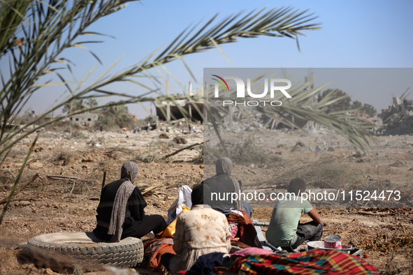 Palestinians collect their belongings and inspect the destruction caused by Israeli airstrikes in eastern Deir al-Balah in central Gaza Stri...