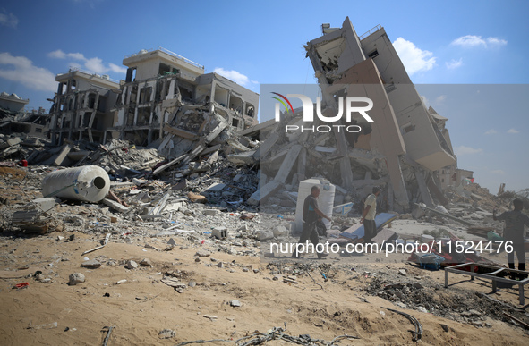 Palestinians collect their belongings and inspect the destruction caused by Israeli airstrikes in eastern Deir al-Balah in central Gaza Stri...