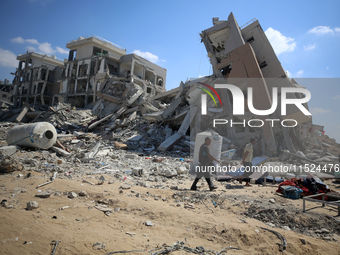 Palestinians collect their belongings and inspect the destruction caused by Israeli airstrikes in eastern Deir al-Balah in central Gaza Stri...