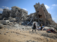 Palestinians collect their belongings and inspect the destruction caused by Israeli airstrikes in eastern Deir al-Balah in central Gaza Stri...