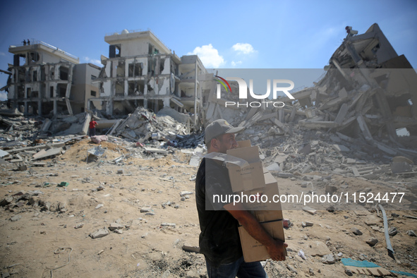 Palestinians collect their belongings and inspect the destruction caused by Israeli airstrikes in eastern Deir al-Balah in central Gaza Stri...