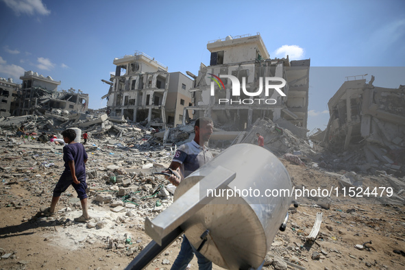 Palestinians collect their belongings and inspect the destruction caused by Israeli airstrikes in eastern Deir al-Balah in central Gaza Stri...