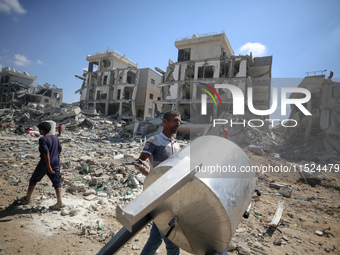 Palestinians collect their belongings and inspect the destruction caused by Israeli airstrikes in eastern Deir al-Balah in central Gaza Stri...