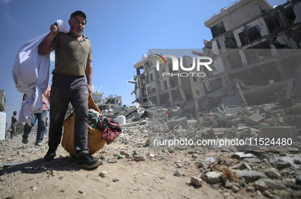 Palestinians collect their belongings and inspect the destruction caused by Israeli airstrikes in eastern Deir al-Balah in central Gaza Stri...