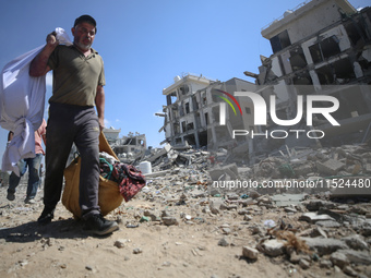 Palestinians collect their belongings and inspect the destruction caused by Israeli airstrikes in eastern Deir al-Balah in central Gaza Stri...