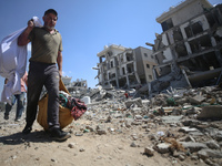 Palestinians collect their belongings and inspect the destruction caused by Israeli airstrikes in eastern Deir al-Balah in central Gaza Stri...