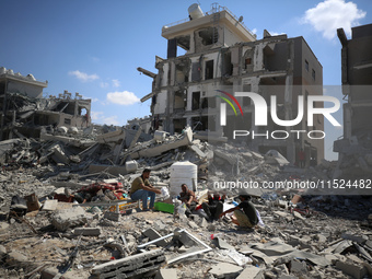 Palestinians collect their belongings and inspect the destruction caused by Israeli airstrikes in eastern Deir al-Balah in central Gaza Stri...