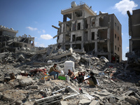 Palestinians collect their belongings and inspect the destruction caused by Israeli airstrikes in eastern Deir al-Balah in central Gaza Stri...