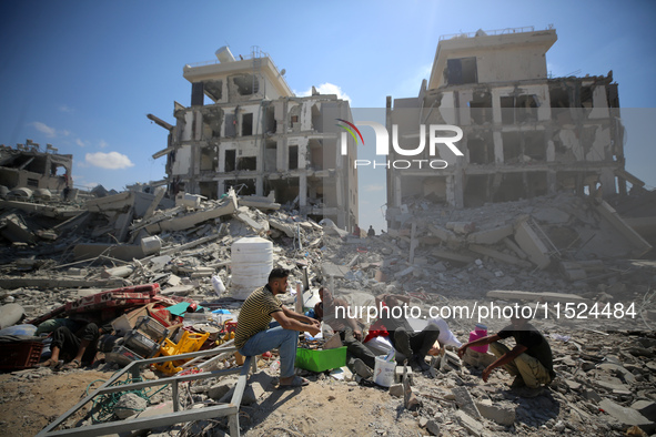 Palestinians collect their belongings and inspect the destruction caused by Israeli airstrikes in eastern Deir al-Balah in central Gaza Stri...