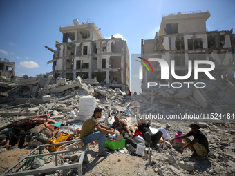 Palestinians collect their belongings and inspect the destruction caused by Israeli airstrikes in eastern Deir al-Balah in central Gaza Stri...