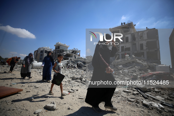 Palestinians collect their belongings and inspect the destruction caused by Israeli airstrikes in eastern Deir al-Balah in central Gaza Stri...