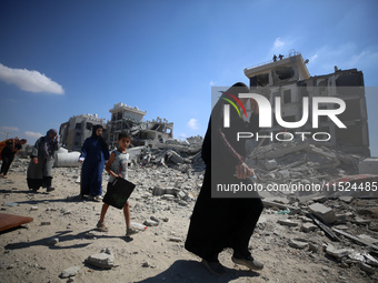 Palestinians collect their belongings and inspect the destruction caused by Israeli airstrikes in eastern Deir al-Balah in central Gaza Stri...