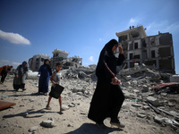 Palestinians collect their belongings and inspect the destruction caused by Israeli airstrikes in eastern Deir al-Balah in central Gaza Stri...