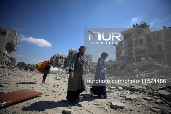 Palestinians collect their belongings and inspect the destruction caused by Israeli airstrikes in eastern Deir al-Balah in central Gaza Stri...