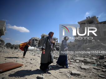 Palestinians collect their belongings and inspect the destruction caused by Israeli airstrikes in eastern Deir al-Balah in central Gaza Stri...