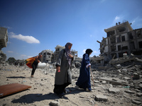 Palestinians collect their belongings and inspect the destruction caused by Israeli airstrikes in eastern Deir al-Balah in central Gaza Stri...