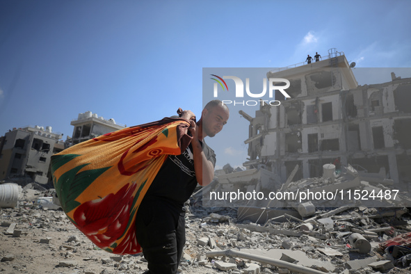 Palestinians collect their belongings and inspect the destruction caused by Israeli airstrikes in eastern Deir al-Balah in central Gaza Stri...