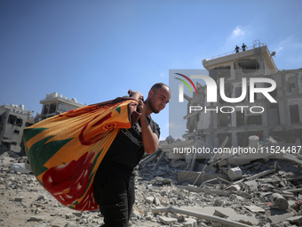 Palestinians collect their belongings and inspect the destruction caused by Israeli airstrikes in eastern Deir al-Balah in central Gaza Stri...