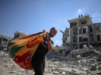 Palestinians collect their belongings and inspect the destruction caused by Israeli airstrikes in eastern Deir al-Balah in central Gaza Stri...