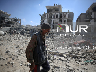 Palestinians collect their belongings and inspect the destruction caused by Israeli airstrikes in eastern Deir al-Balah in central Gaza Stri...