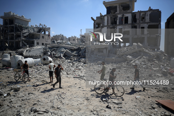 Palestinians collect their belongings and inspect the destruction caused by Israeli airstrikes in eastern Deir al-Balah in central Gaza Stri...