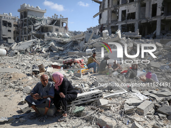 Palestinians collect their belongings and inspect the destruction caused by Israeli airstrikes in eastern Deir al-Balah in central Gaza Stri...