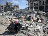 Palestinians collect their belongings and inspect the destruction caused by Israeli airstrikes in eastern Deir al-Balah in central Gaza Stri...