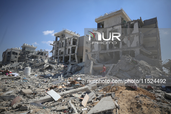 Palestinians collect their belongings and inspect the destruction caused by Israeli airstrikes in eastern Deir al-Balah in central Gaza Stri...