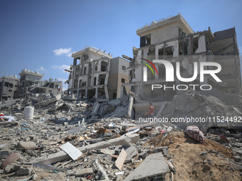 Palestinians collect their belongings and inspect the destruction caused by Israeli airstrikes in eastern Deir al-Balah in central Gaza Stri...