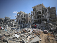 Palestinians collect their belongings and inspect the destruction caused by Israeli airstrikes in eastern Deir al-Balah in central Gaza Stri...