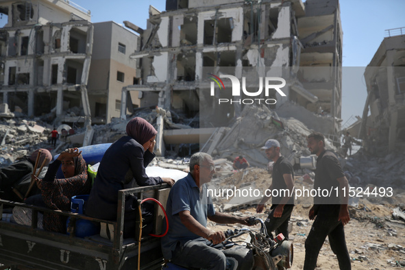 Palestinians collect their belongings and inspect the destruction caused by Israeli airstrikes in eastern Deir al-Balah in central Gaza Stri...