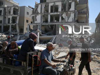 Palestinians collect their belongings and inspect the destruction caused by Israeli airstrikes in eastern Deir al-Balah in central Gaza Stri...