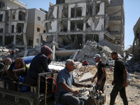 Palestinians collect their belongings and inspect the destruction caused by Israeli airstrikes in eastern Deir al-Balah in central Gaza Stri...