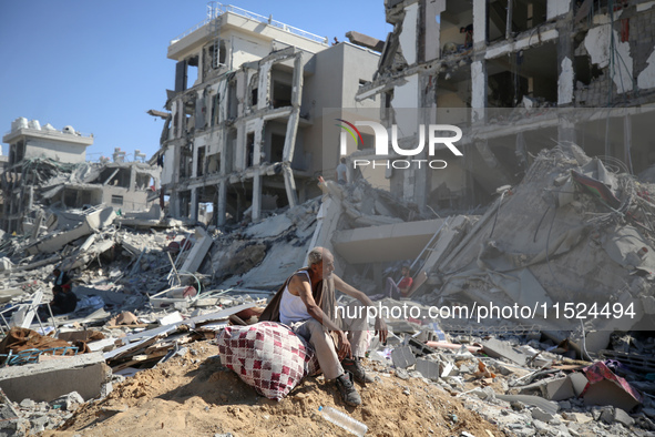 Palestinians collect their belongings and inspect the destruction caused by Israeli airstrikes in eastern Deir al-Balah in central Gaza Stri...