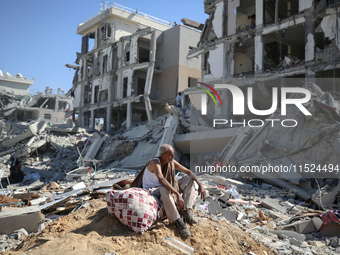 Palestinians collect their belongings and inspect the destruction caused by Israeli airstrikes in eastern Deir al-Balah in central Gaza Stri...