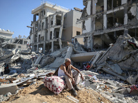 Palestinians collect their belongings and inspect the destruction caused by Israeli airstrikes in eastern Deir al-Balah in central Gaza Stri...