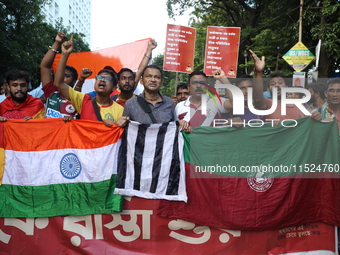 Supporters of the arch-rival football clubs East Bengal and Mohammedan Sporting Club shout slogans during a protest march against the rape a...