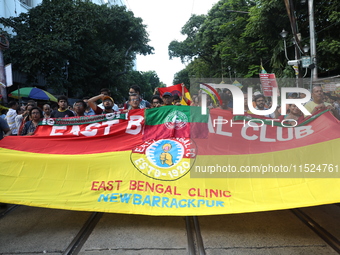 Supporters of the arch-rival football clubs East Bengal and Mohammedan Sporting Club shout slogans during a protest march against the rape a...