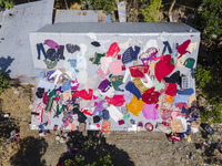 A flood-affected family dries clothes and essential items soaked in flood water on the roof of a house in Gopal village of Chagalnaiya upazi...