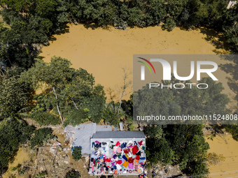 A flood-affected family dries clothes and essential items soaked in flood water on the roof of a house in Gopal village of Chagalnaiya upazi...