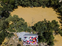 A flood-affected family dries clothes and essential items soaked in flood water on the roof of a house in Gopal village of Chagalnaiya upazi...