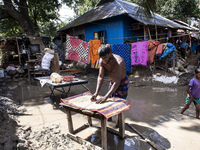 A flood-affected person tries to dry rice in the small sun in the Gopal area of Chagalnaiya upazila in Feni district in Chittagong division...