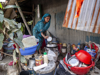 A member of a flood-affected family cooks lunch outside the house among the messy belongings in Gopal area of Chagalnaia upazila in Feni dis...