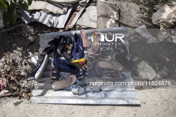 A flood-affected family puts their shoes on a tin to dry in the little sun in the Gopal area of Chagalnaiya upazila, Feni district, Chittago...