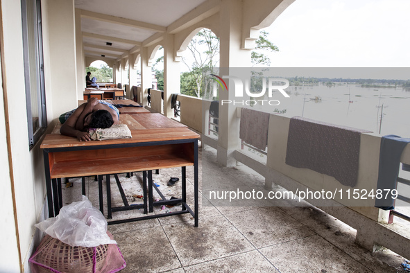 A person sleeps on a table on the balcony of a shelter in Chagalnaya Upazila, Feni District, Chittagong Division, Bangladesh, on August 29,...