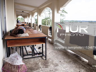 A person sleeps on a table on the balcony of a shelter in Chagalnaya Upazila, Feni District, Chittagong Division, Bangladesh, on August 29,...