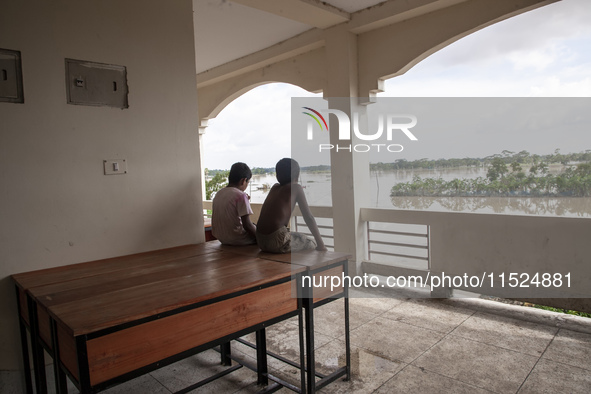 Two small boys sit on a table on the balcony of a shelter watching the flooding outside in Chagalnaiya Upazila, Feni District, Chittagong Di...