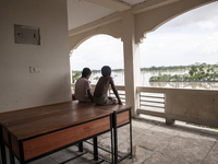 Two small boys sit on a table on the balcony of a shelter watching the flooding outside in Chagalnaiya Upazila, Feni District, Chittagong Di...